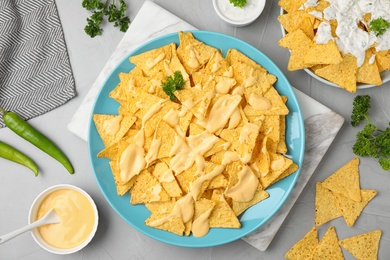 Photo of Mexican nacho chips with sauce on grey table, flat lay