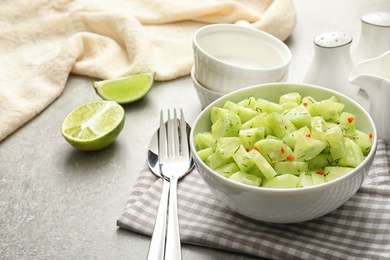 Photo of Delicious cucumber salad in bowl served on table. Space for text