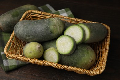 Photo of Green daikon radishes in wicker basket on wooden table
