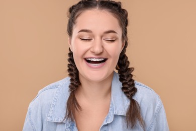 Laughing woman with braces on beige background