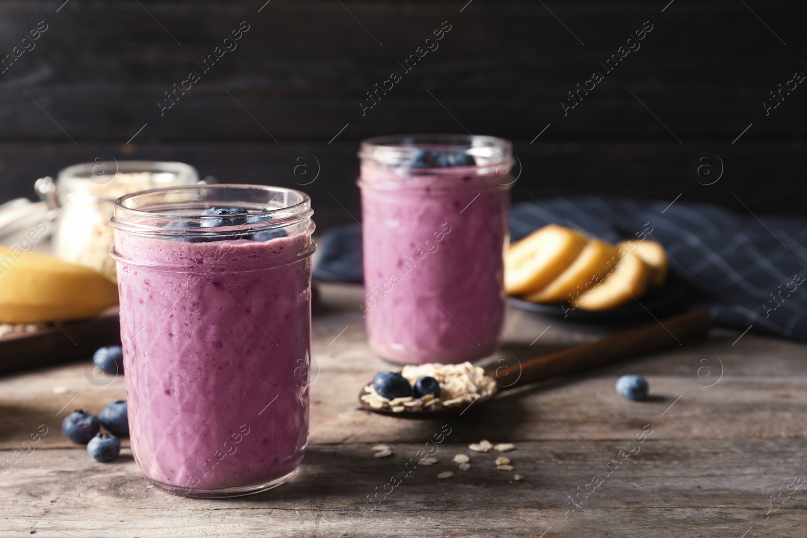 Photo of Jars with blueberry smoothies on wooden table