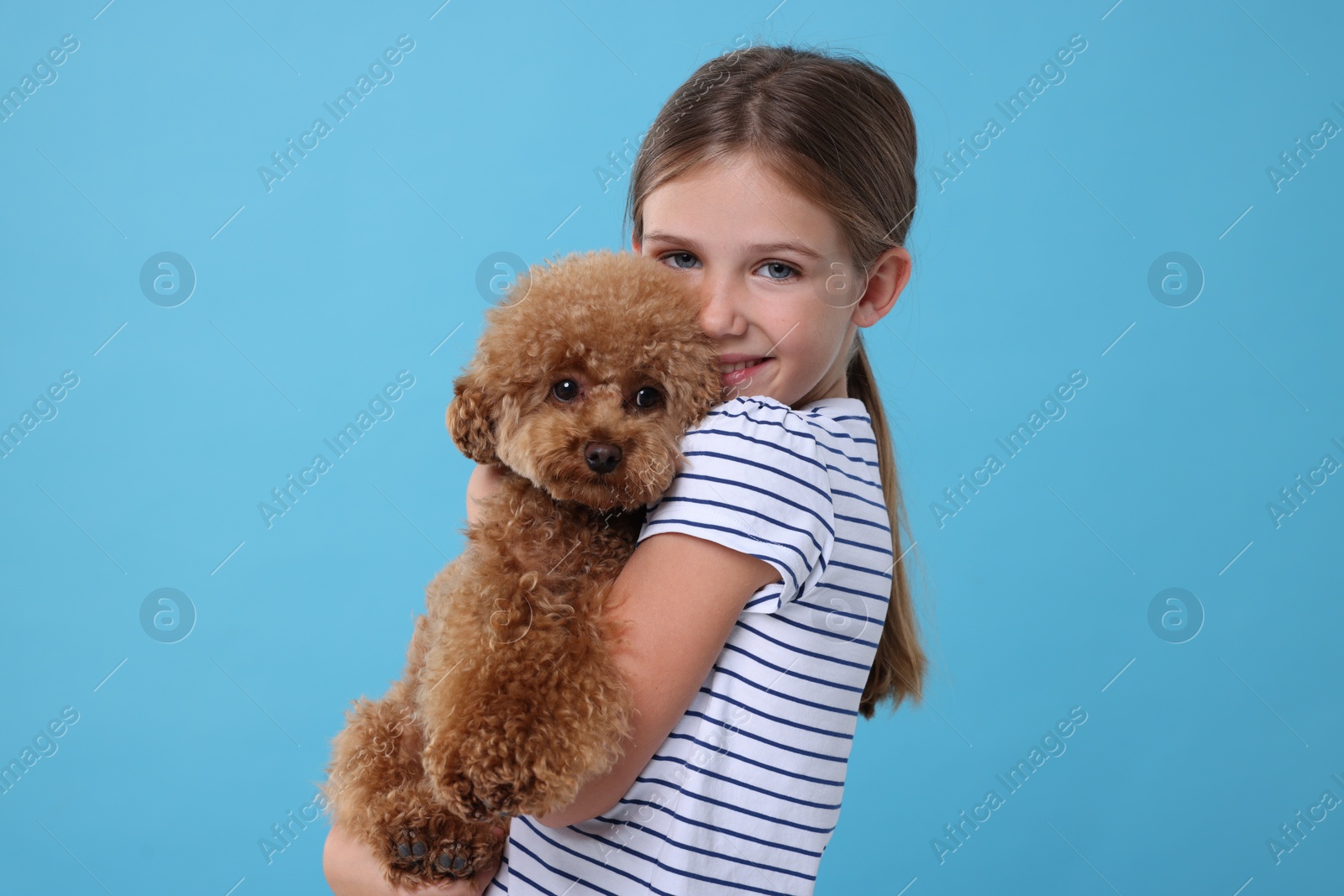 Photo of Little child with cute puppy on light blue background. Lovely pet