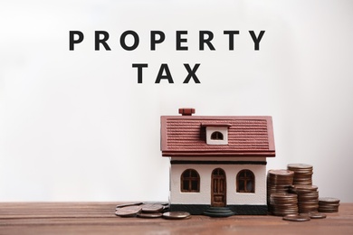 Image of Text Property Tax near coins and house model on light background