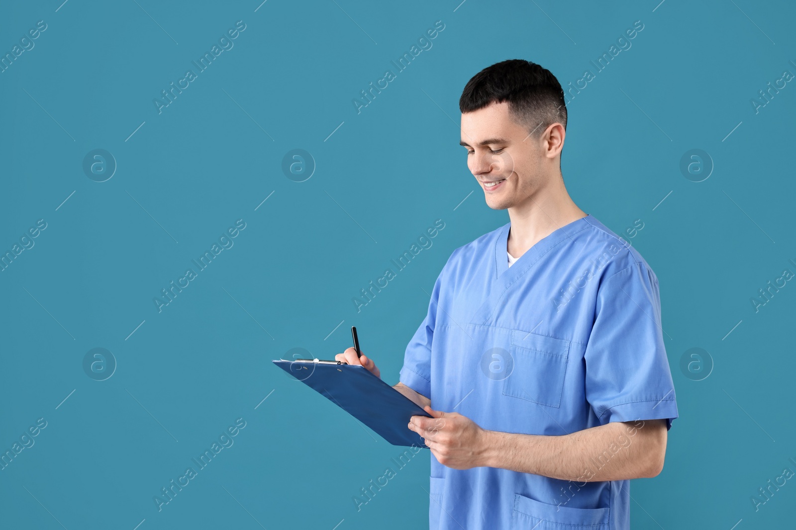 Photo of Portrait of smiling medical assistant with clipboard on light blue background. Space for text