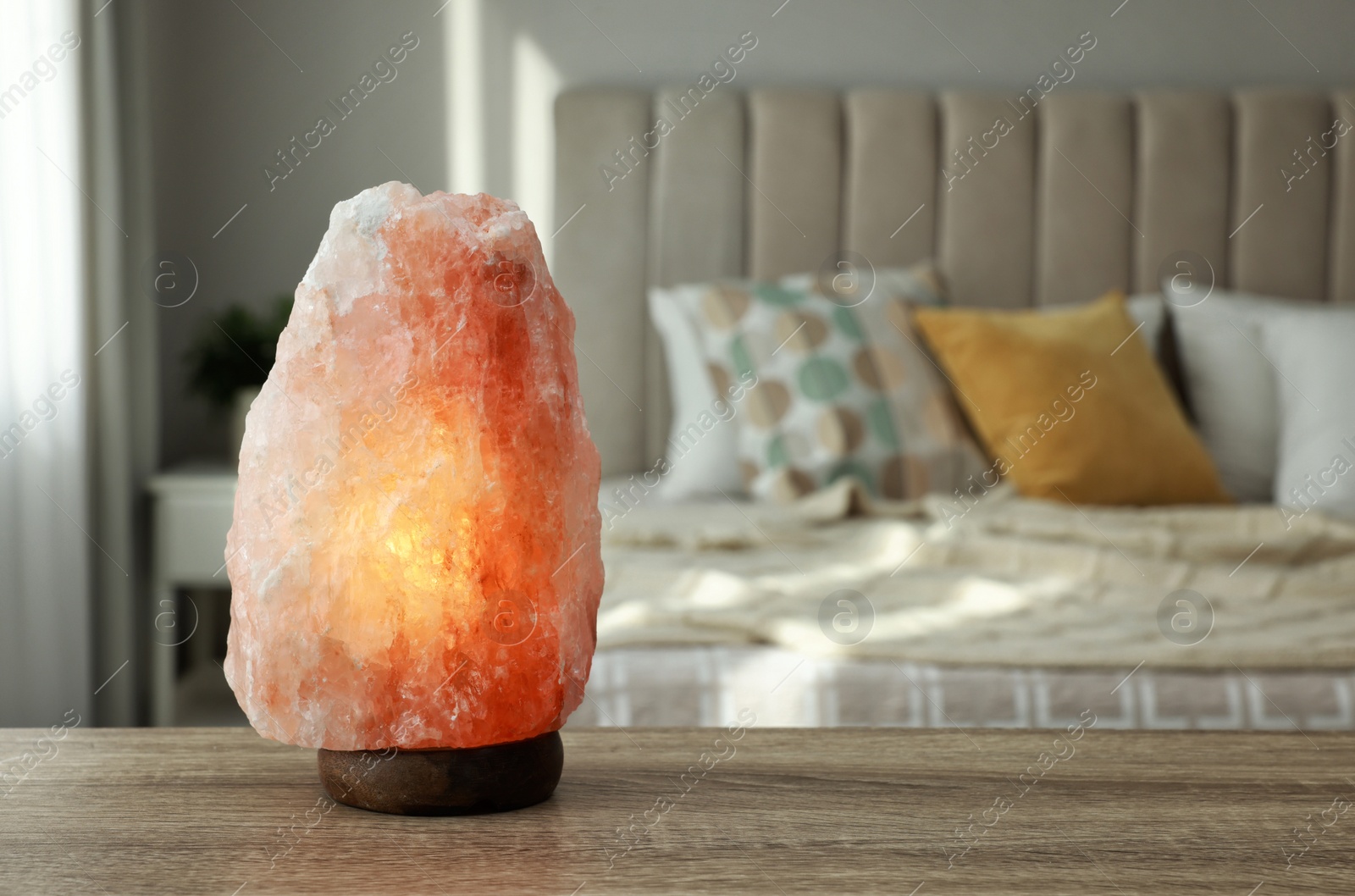 Photo of Beautiful Himalayan salt lamp on wooden table in bedroom, space for text