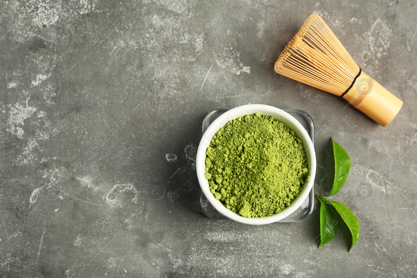 Photo of Matcha tea in bowl, whisk and green leaves on table, top view