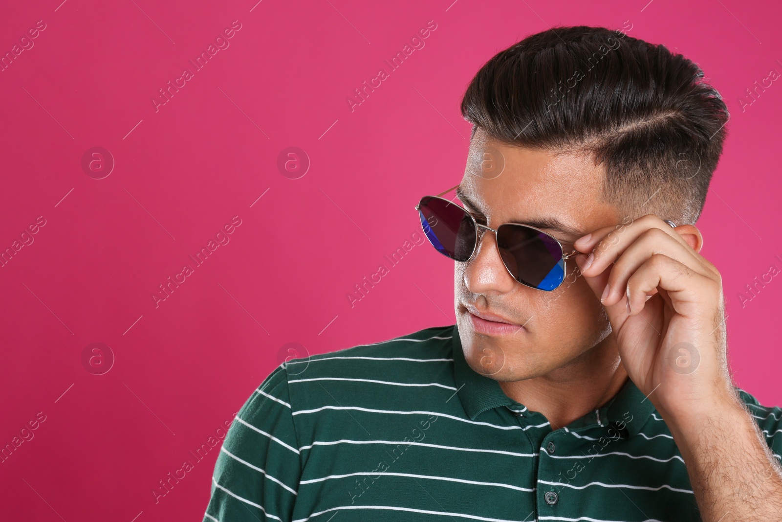 Photo of Handsome man wearing sunglasses on pink background, closeup. Space for text