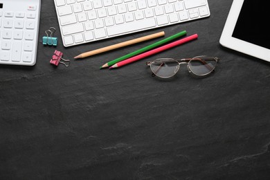 Photo of Stationery, glasses and computer keyboard on black table, flat lay. Space for text