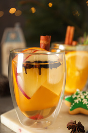 Photo of Aromatic white mulled wine in glass on board, closeup