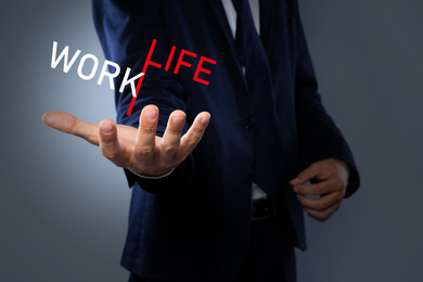 Businessman showing balance between life and work on grey background, closeup