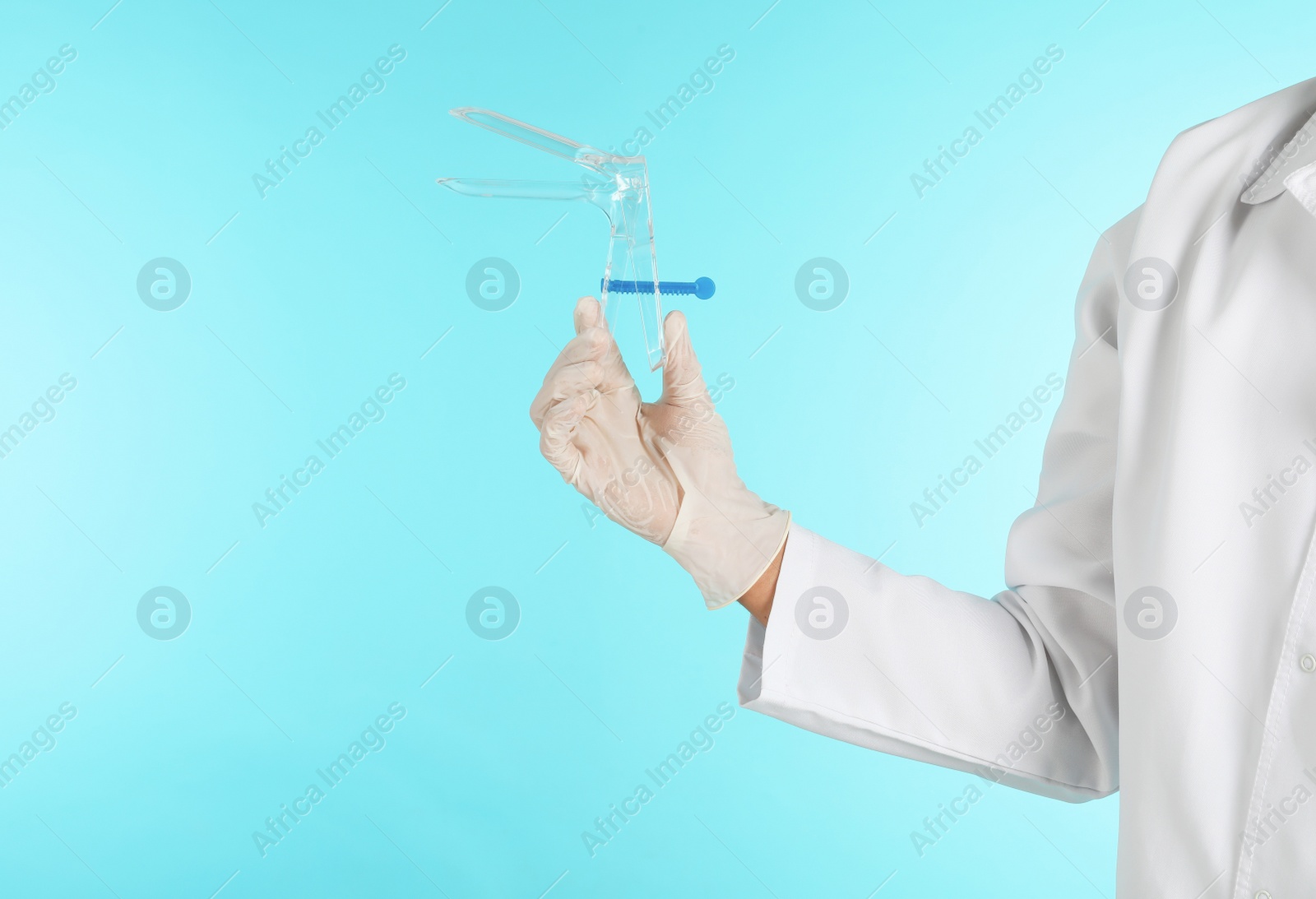 Photo of Male doctor holding disposable speculum on color background, closeup with space for text. Medical object