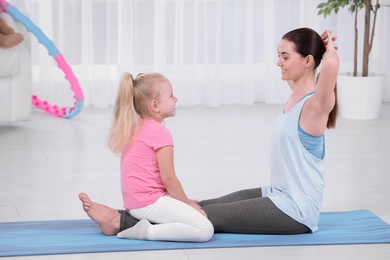 Photo of Sportive woman doing fitness exercises with daughter at home