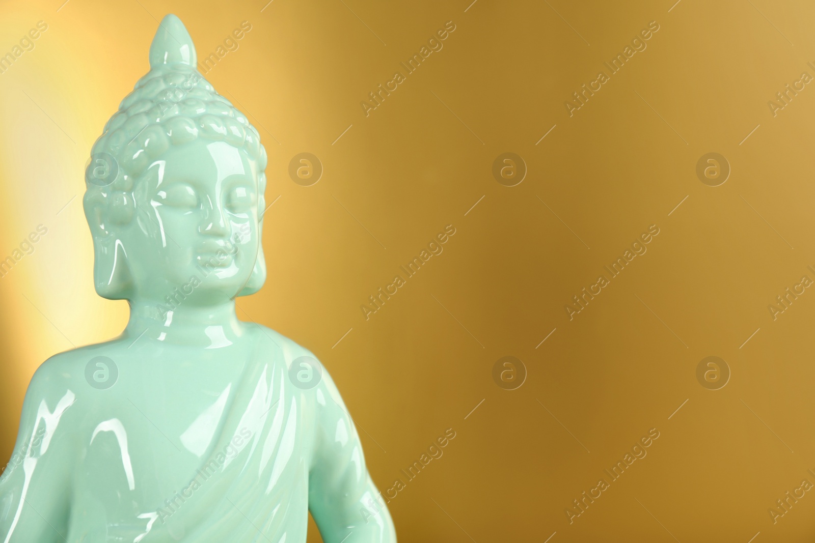 Photo of Buddha statue on golden background, closeup. Space for text