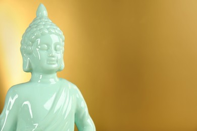 Photo of Buddha statue on golden background, closeup. Space for text