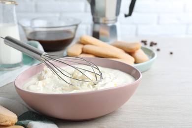 Photo of Bowl with mascarpone cream on white wooden table. Making tiramisu cake