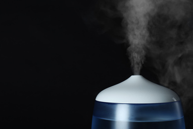 Photo of Modern air humidifier on black background, closeup. Space for text