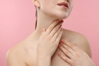 Woman touching her neck on pink background, closeup