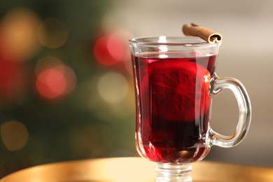 Photo of Delicious mulled wine in glass cup against blurred background, closeup. Space for text