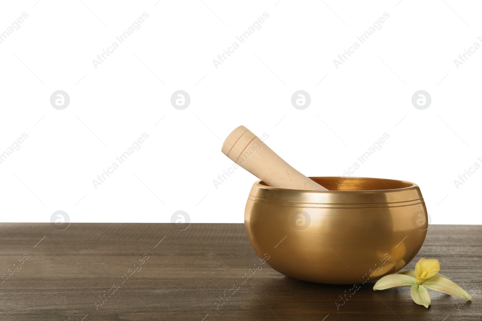 Photo of Golden singing bowl, mallet and flower on wooden table against white background, space for text