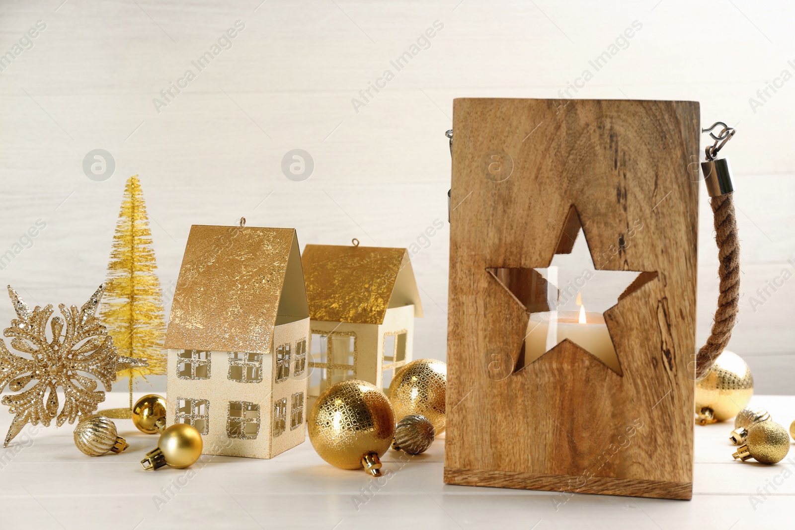 Photo of Christmas lantern with burning candle and festive decor on white wooden table