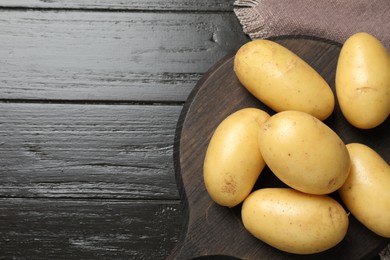 Photo of Fresh raw potatoes on wooden table, top view. Space for text