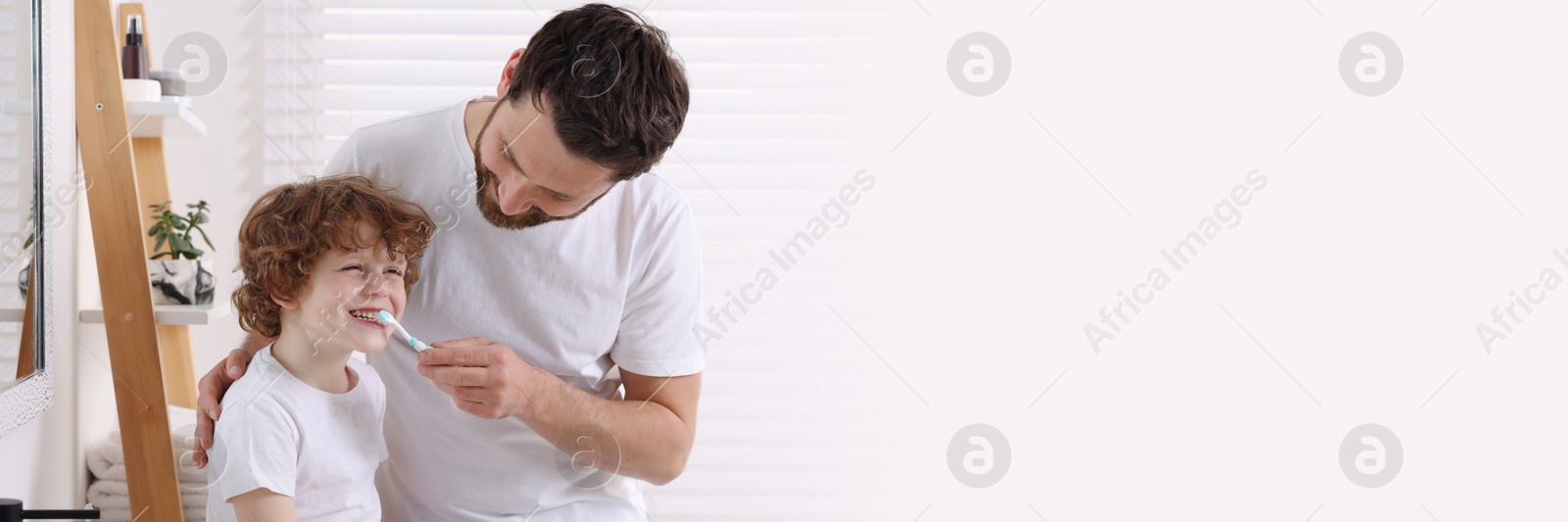 Image of Father helping his son to brush teeth in bathroom. Banner design with space for text