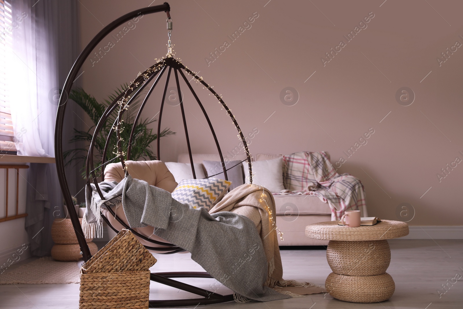 Photo of Cozy hanging chair with fairy lights in modern living room. Interior design