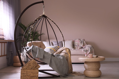 Cozy hanging chair with fairy lights in modern living room. Interior design