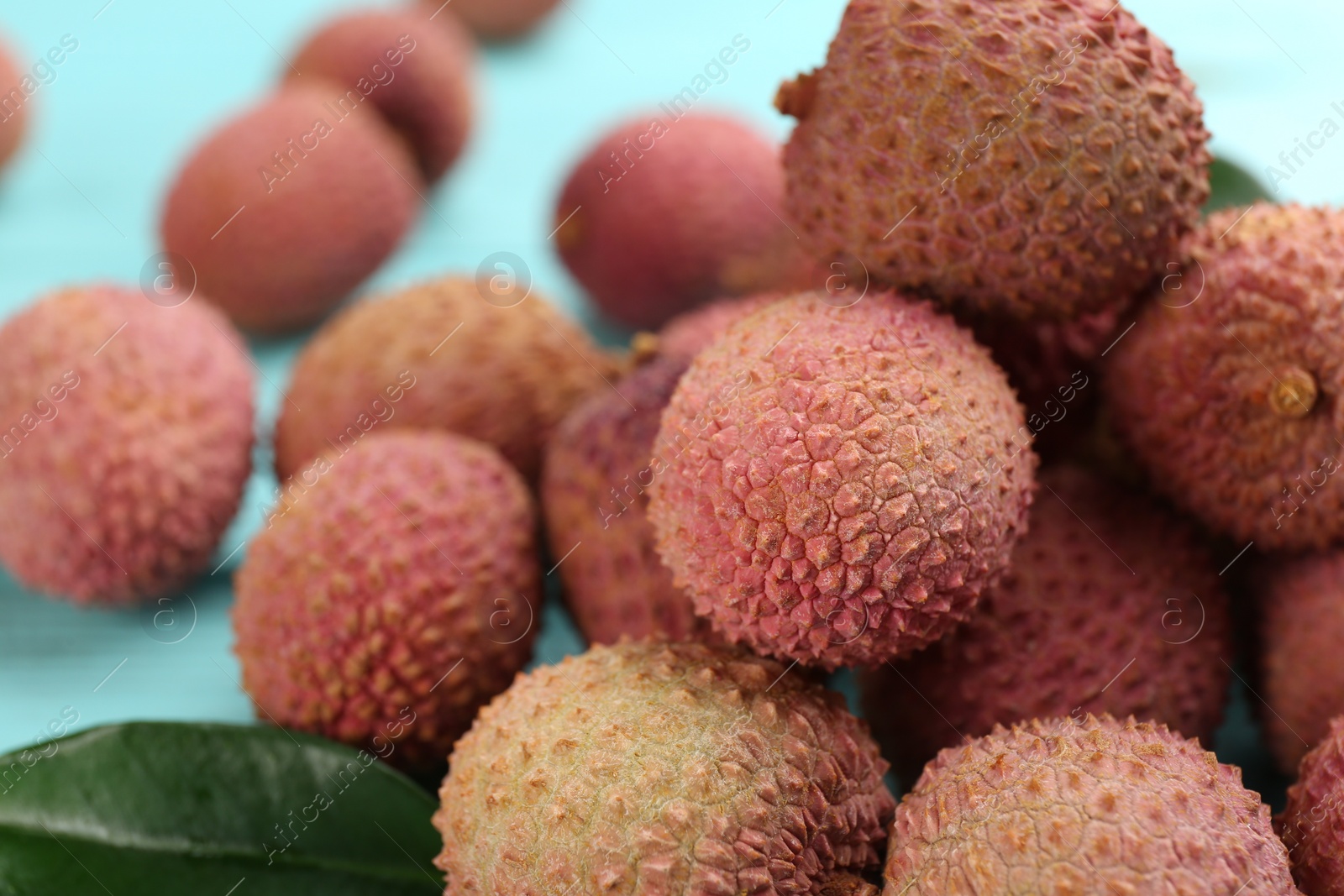 Photo of Fresh ripe lychee fruits on light blue table, closeup