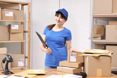 Parcel packing. Post office worker with clipboard at wooden table indoors