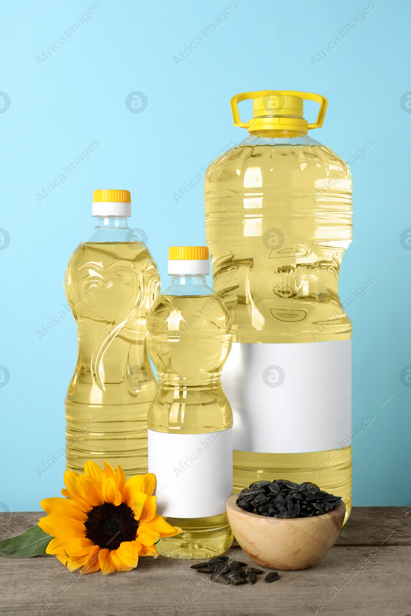 Photo of Bottles of cooking oil, sunflower and seeds on wooden table