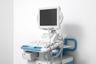 Photo of Ultrasound machine near white wall. Medical equipment
