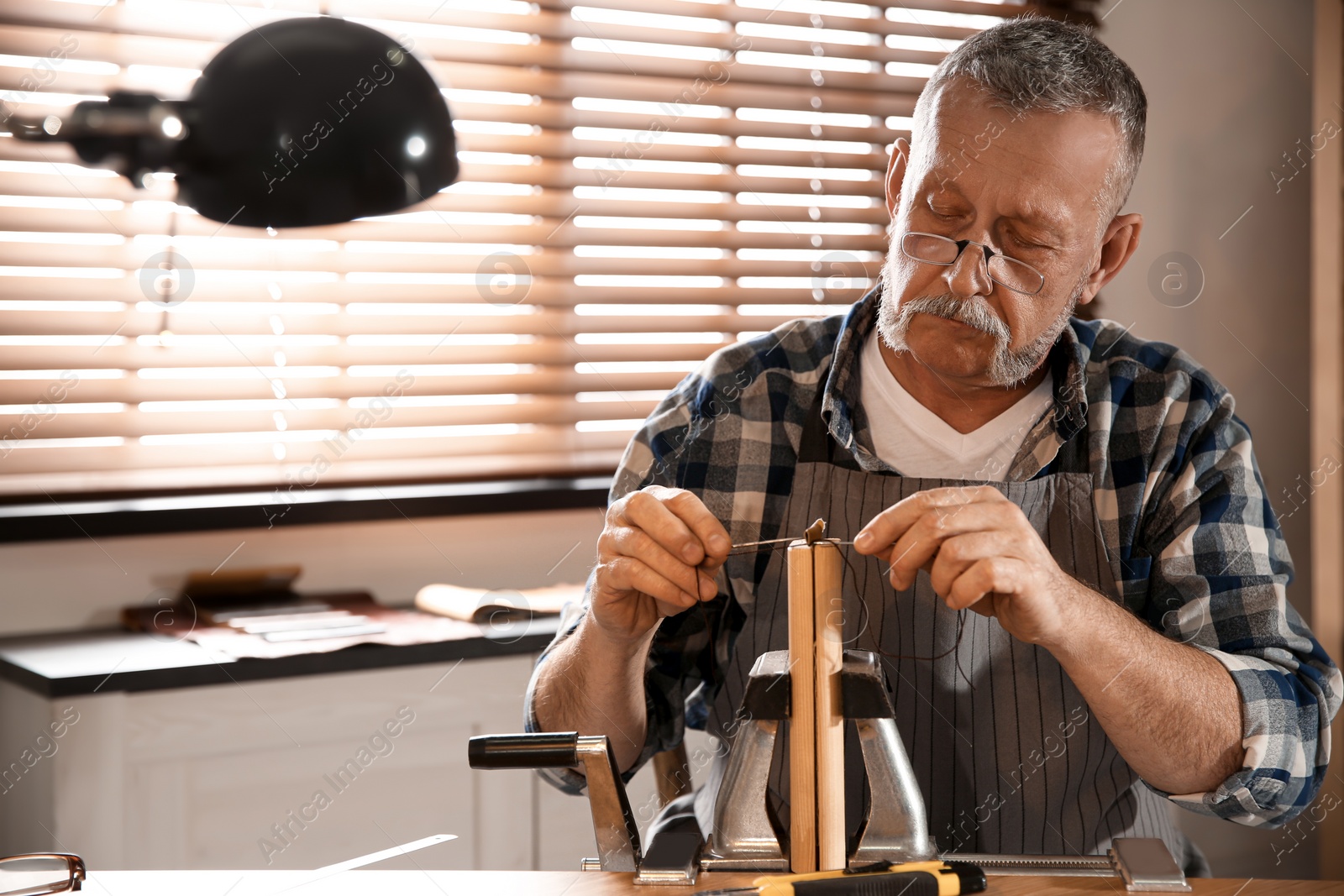 Photo of Man sewing piece of leather in workshop