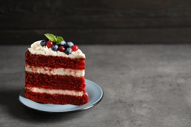 Photo of Plate with piece of delicious homemade red velvet cake and space for text on blurred background