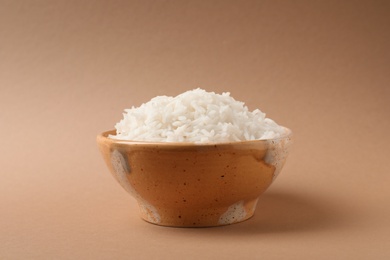 Bowl of tasty cooked rice on color background