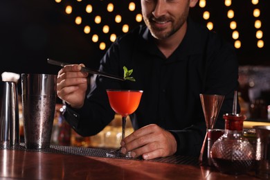 Photo of Bartender preparing fresh alcoholic cocktail in bar, closeup