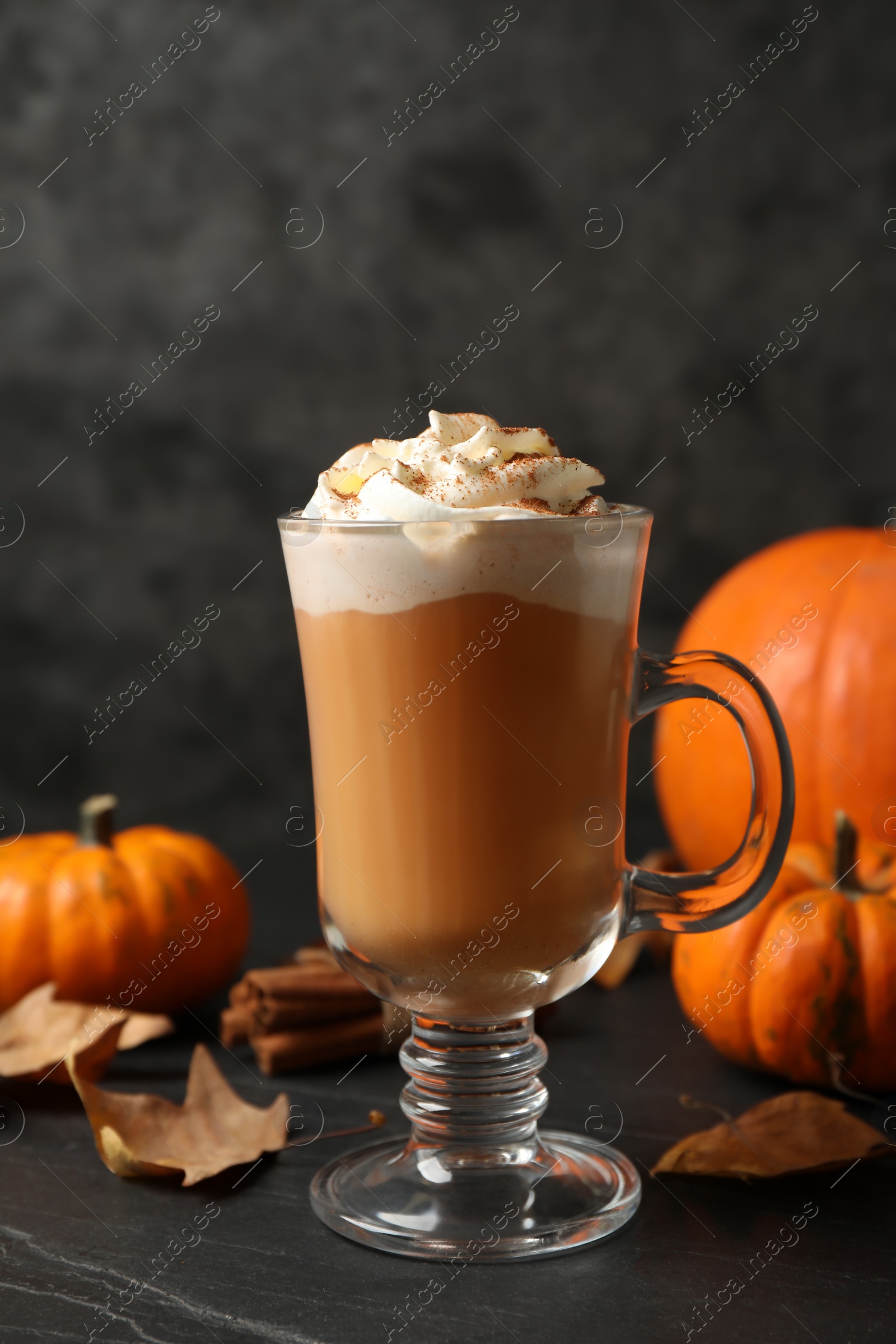 Photo of Delicious pumpkin latte on black slate table, closeup