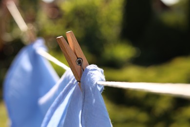 Photo of Clean clothes drying in garden, closeup. Focus on clothespin