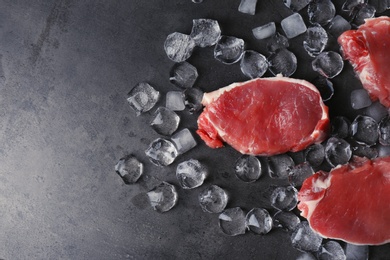 Flat lay composition with raw meat, ice cubes and space for text on dark background