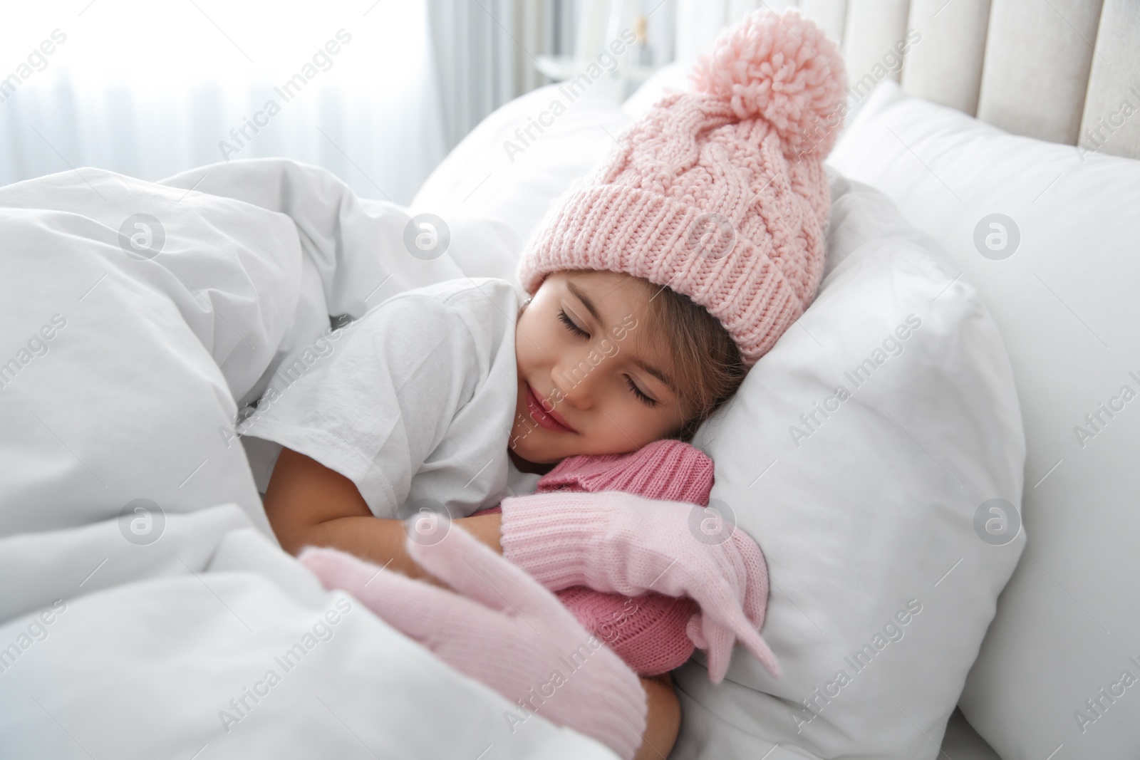 Photo of Ill girl with hot water bottle suffering from cold in bed at home