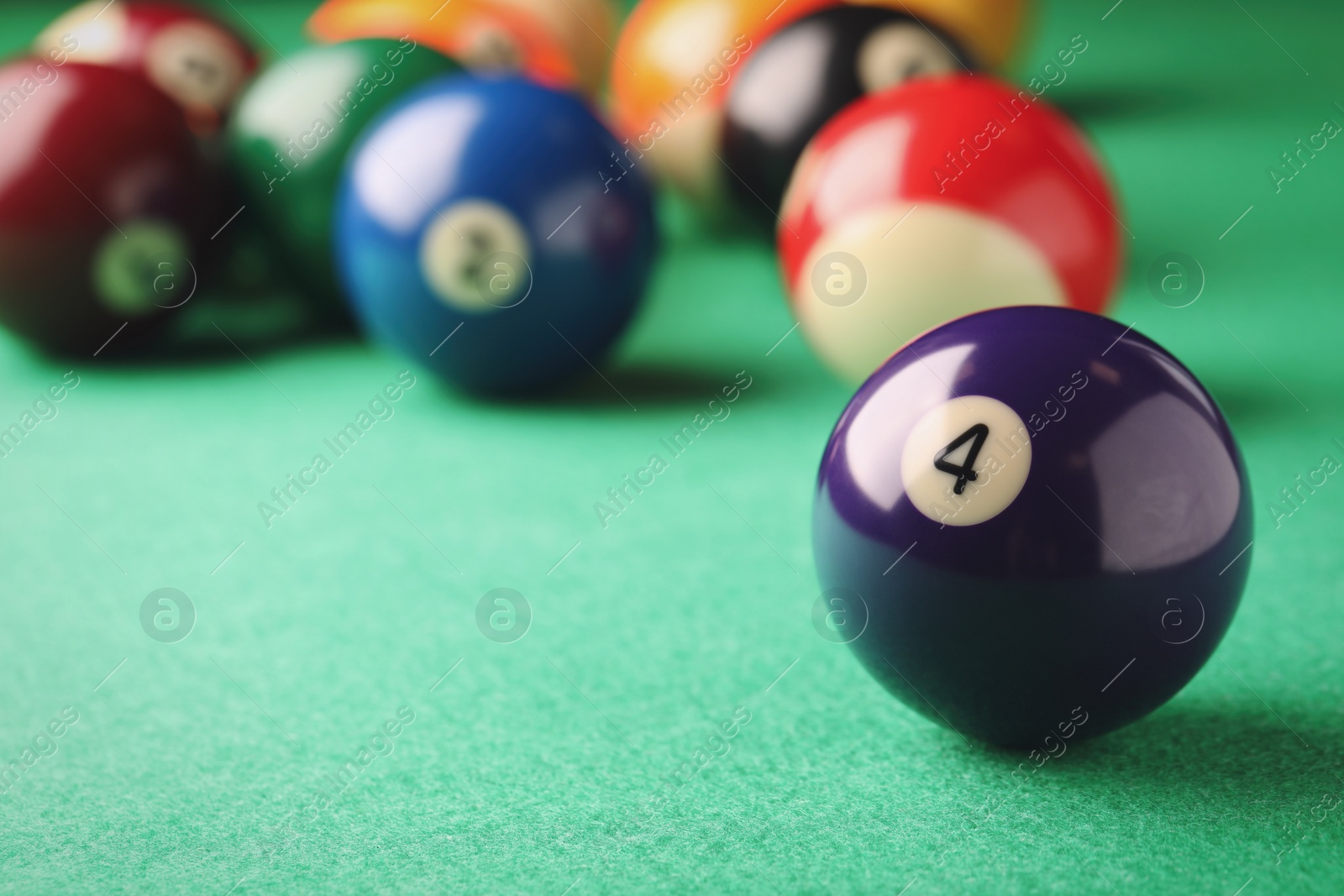 Photo of Billiard ball with number 4 on green table, closeup. Space for text