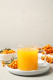 Photo of Delicious sea buckthorn tea and fresh berries on light grey table. Space for text