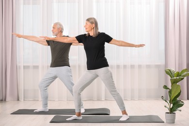 Senior couple practicing yoga on mats at home