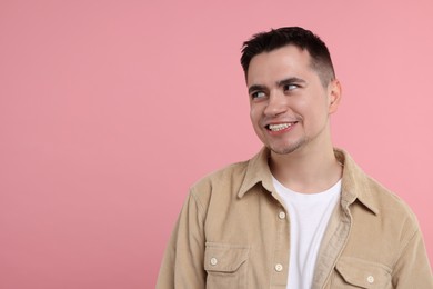 Photo of Portrait of embarrassed young man on pink background, space for text