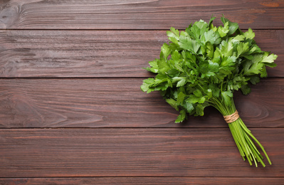 Photo of Bunch of fresh green parsley on wooden table, top view. Space for text