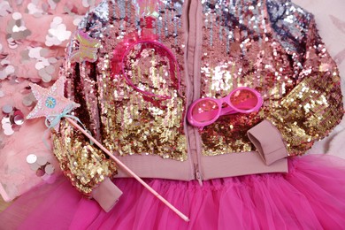 Photo of Stylish carnival costume with sequins, sunglasses, headband and wand on pink fabric, above view