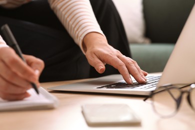 Woman with modern laptop learning at table indoors, closeup