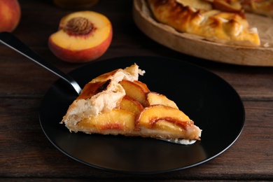 Photo of Piece of delicious fresh peach pie served on wooden table