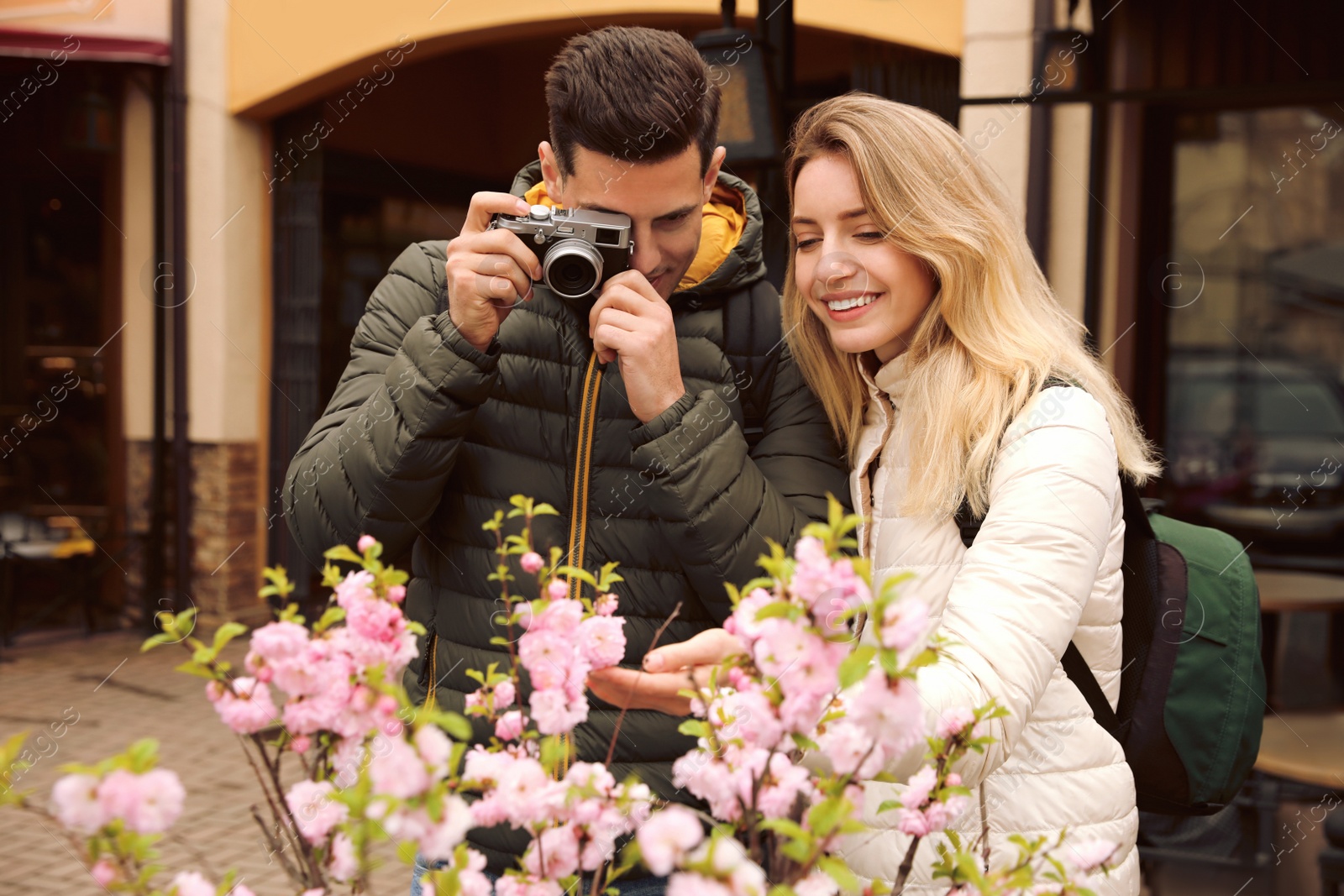 Photo of Tourists with camera taking photo of blossoming tree on city street