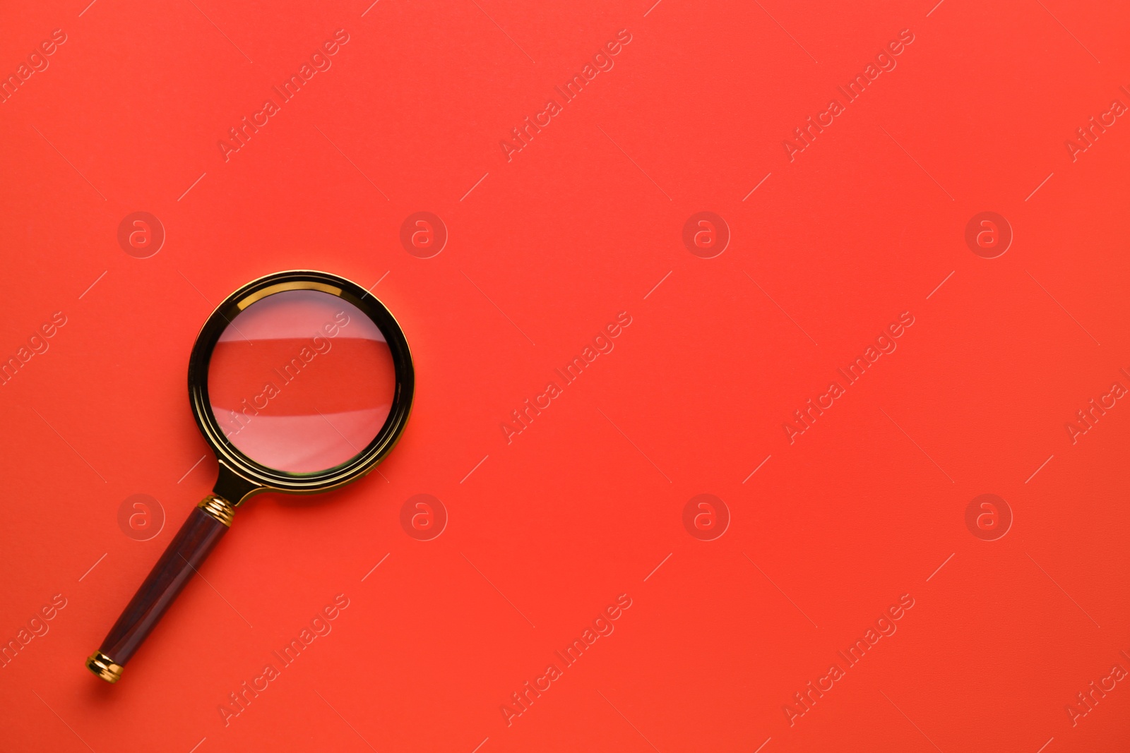 Photo of Magnifying glass on red background, top view. Space for text